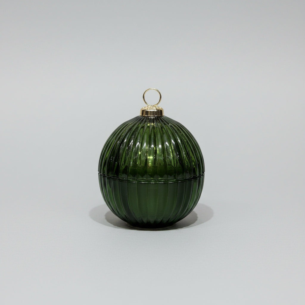 Green glass ornament with ribbed texture on a textured surface