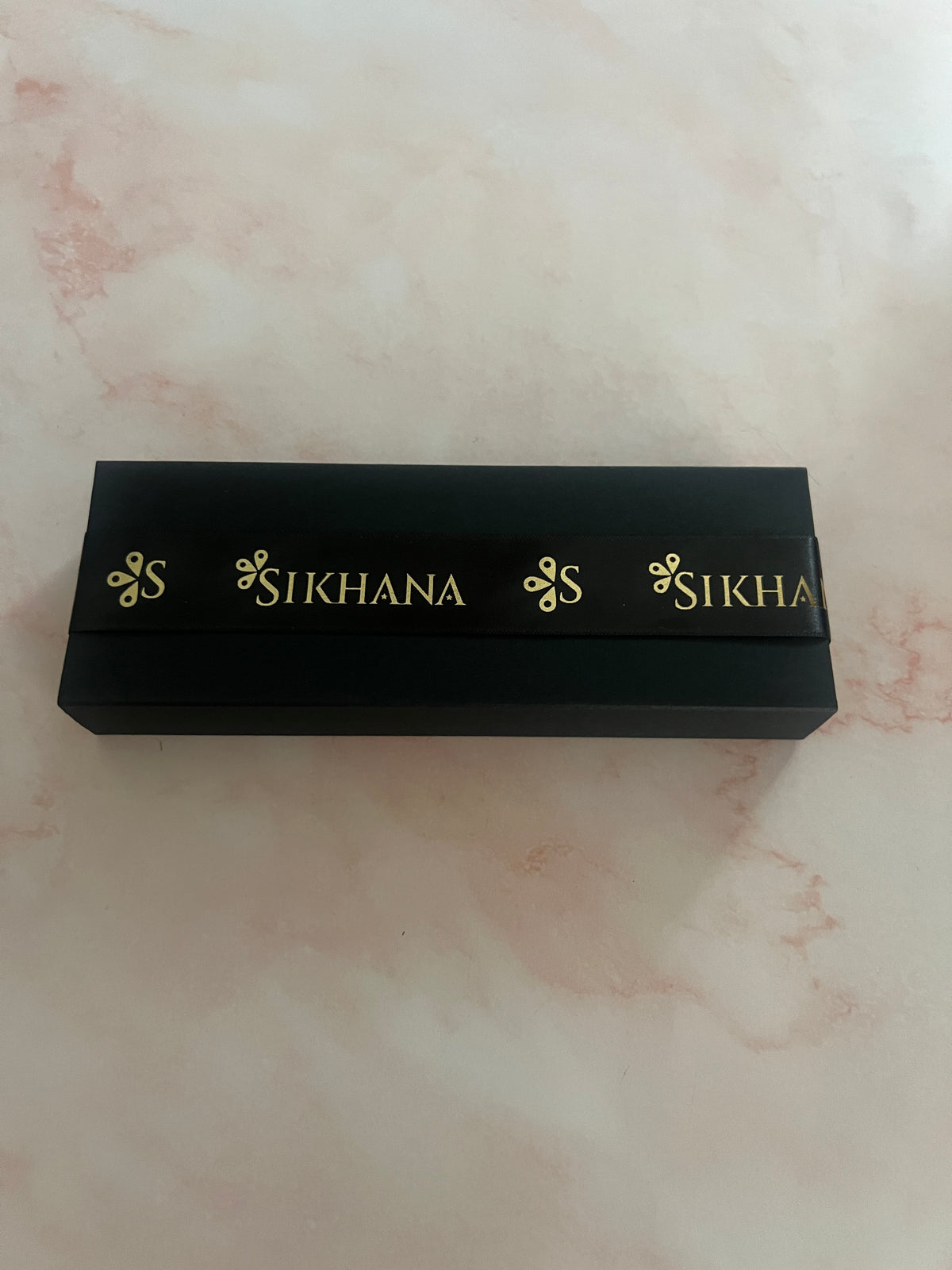 Closed black Sikhana perfume gift box with gold-branded ribbon