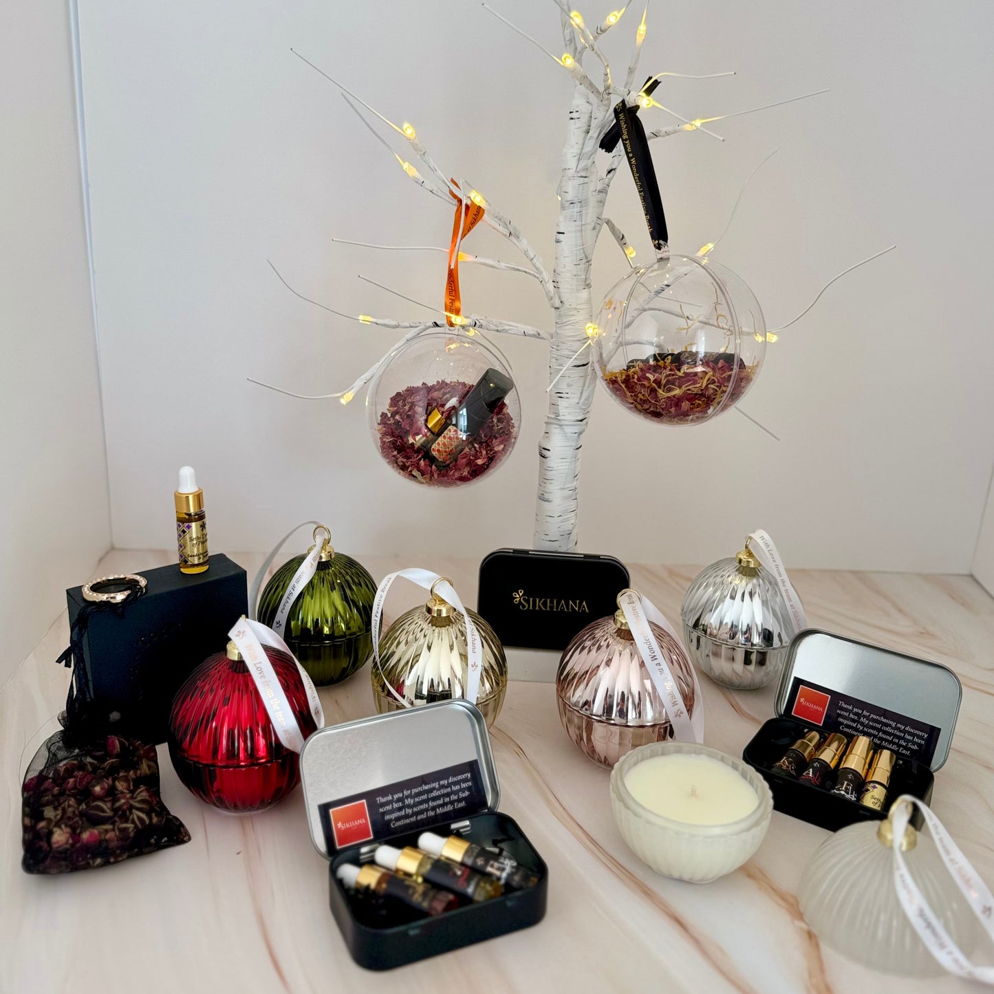 Decorative items including ornaments, candles, and a small tree with lights on a white surface.