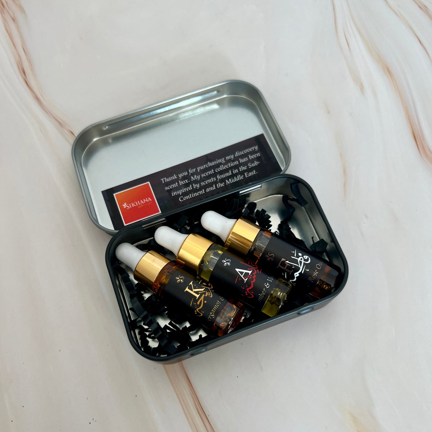 Small black metal case with glass oud droppers.