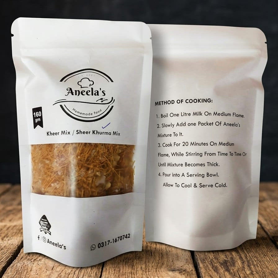 Two packages of Aneela's Kheer Mix on a wooden surface with a dark background