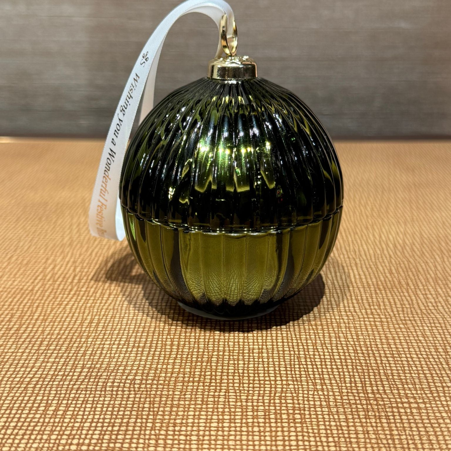 Green glass ornament with ribbed texture on a textured surface
