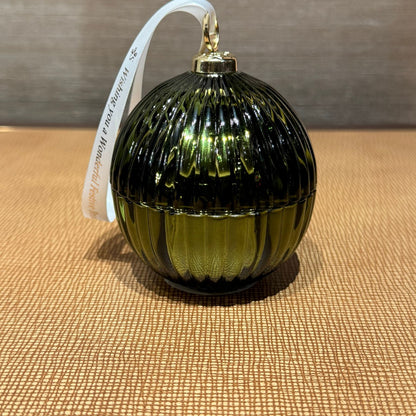 Green glass ornament with ribbed texture on a textured surface