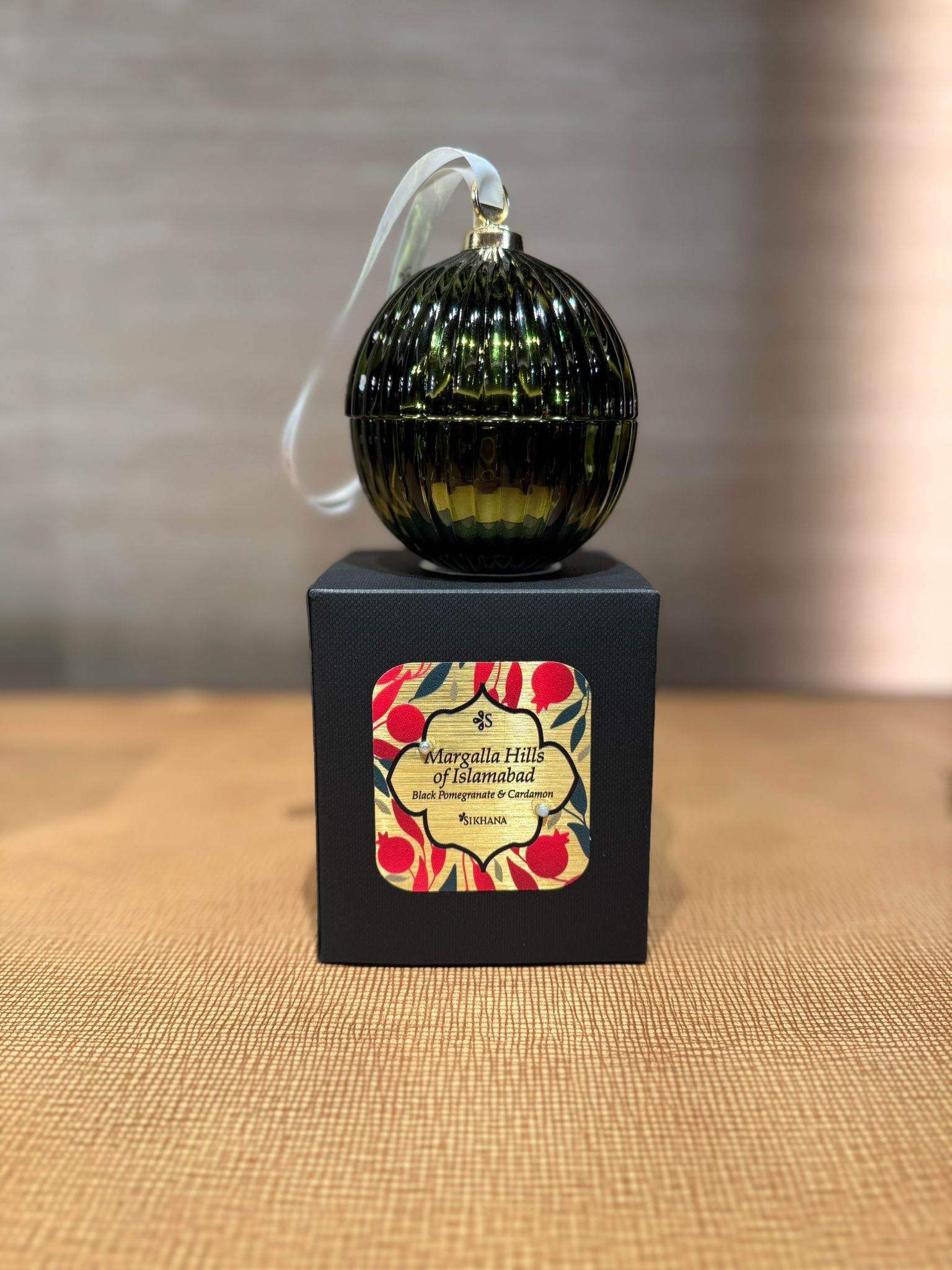 Decorative ornament on a black stand with a colorful label against a neutral background