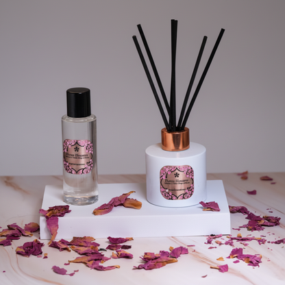Diffuser and bottle with floral design on a textured surface with dried flowers.