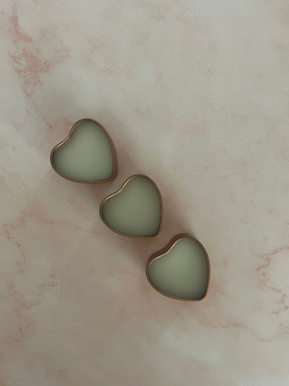 Three gold heart-shaped jars of solid perfume with lids removed