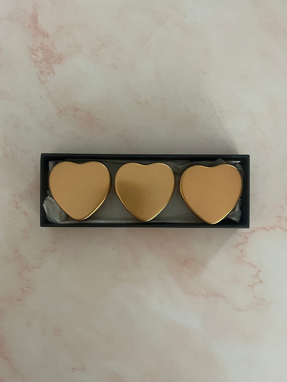 Sikhana gift box holding three gold heart-shaped solid perfume jars with lids