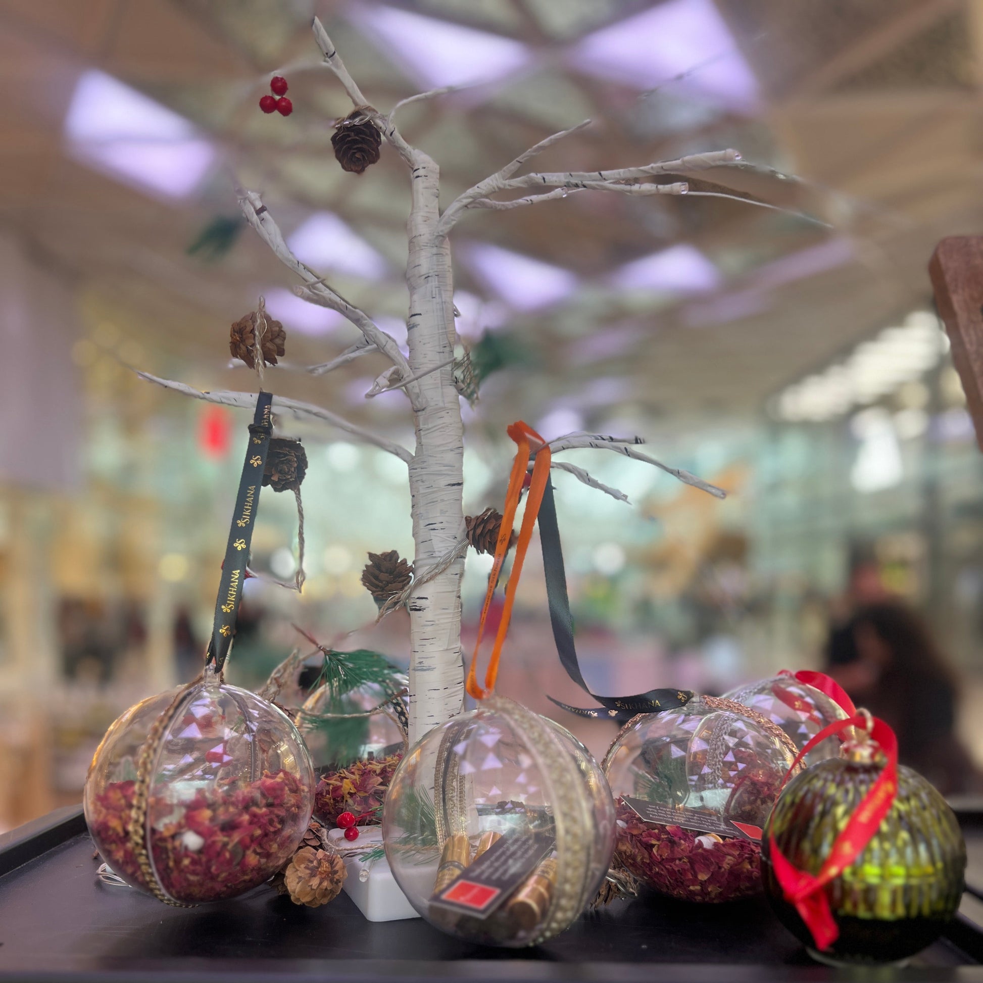 Decorative glass spheres with Christmas ornaments on a black surface.