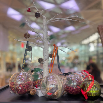 Decorative glass spheres with Christmas ornaments on a black surface.