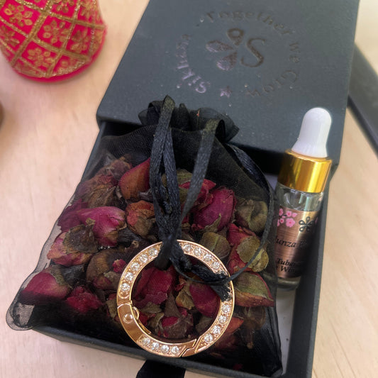 Gold ring with gemstone, dried flowers, and a black box on a wooden surface
