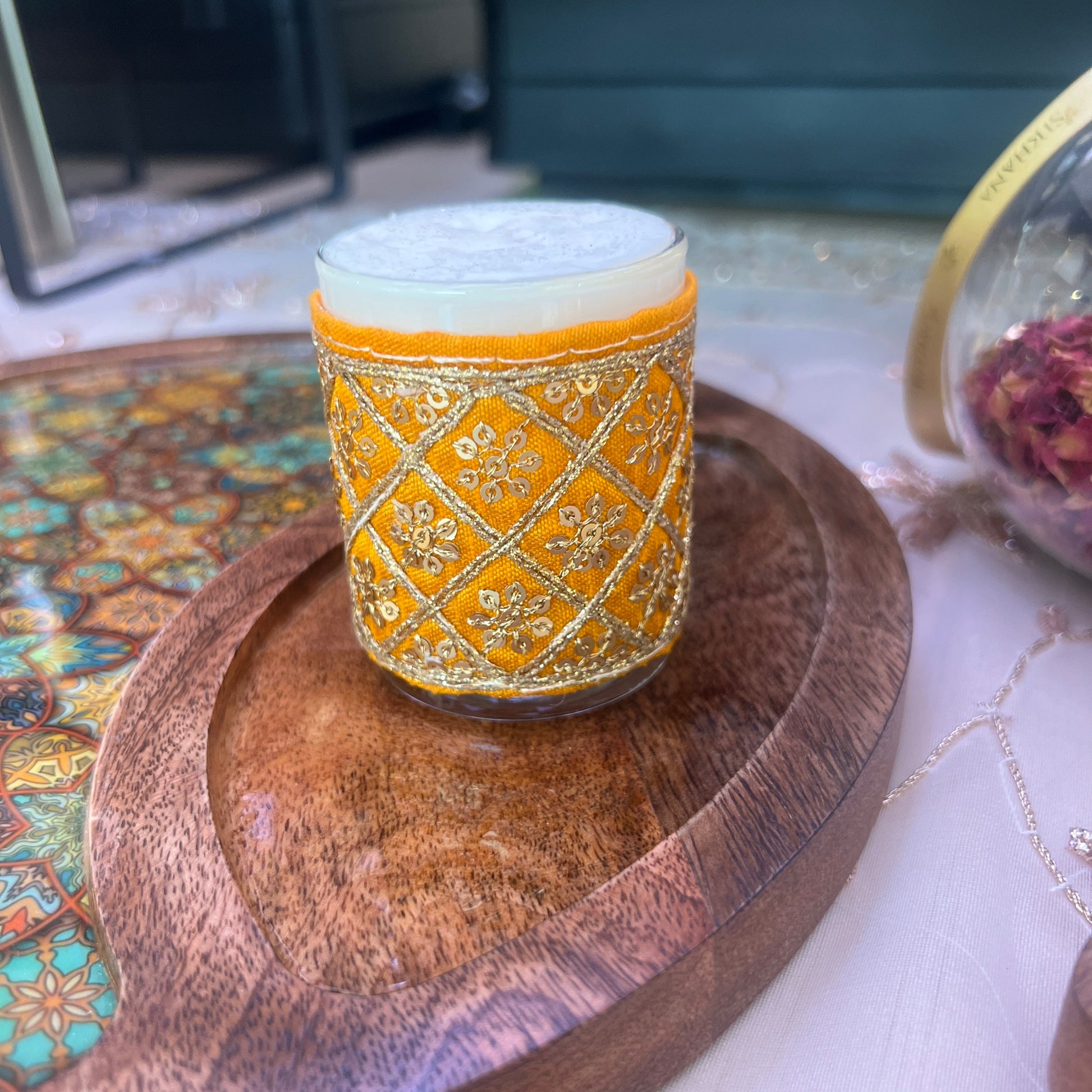 Decorative candle with gold and white pattern on a wooden surface