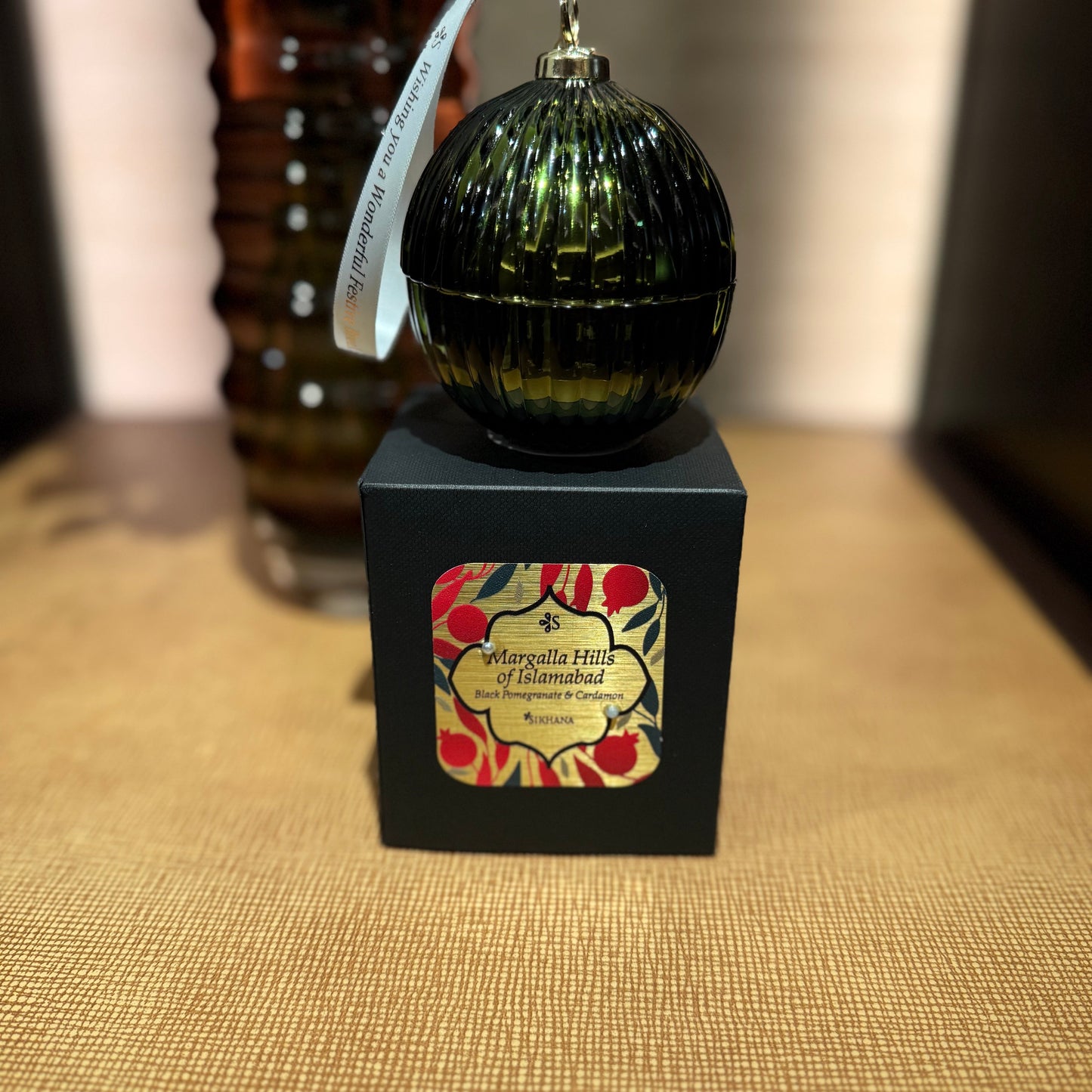 Decorative ornament on a black box with floral design, placed on a textured surface.