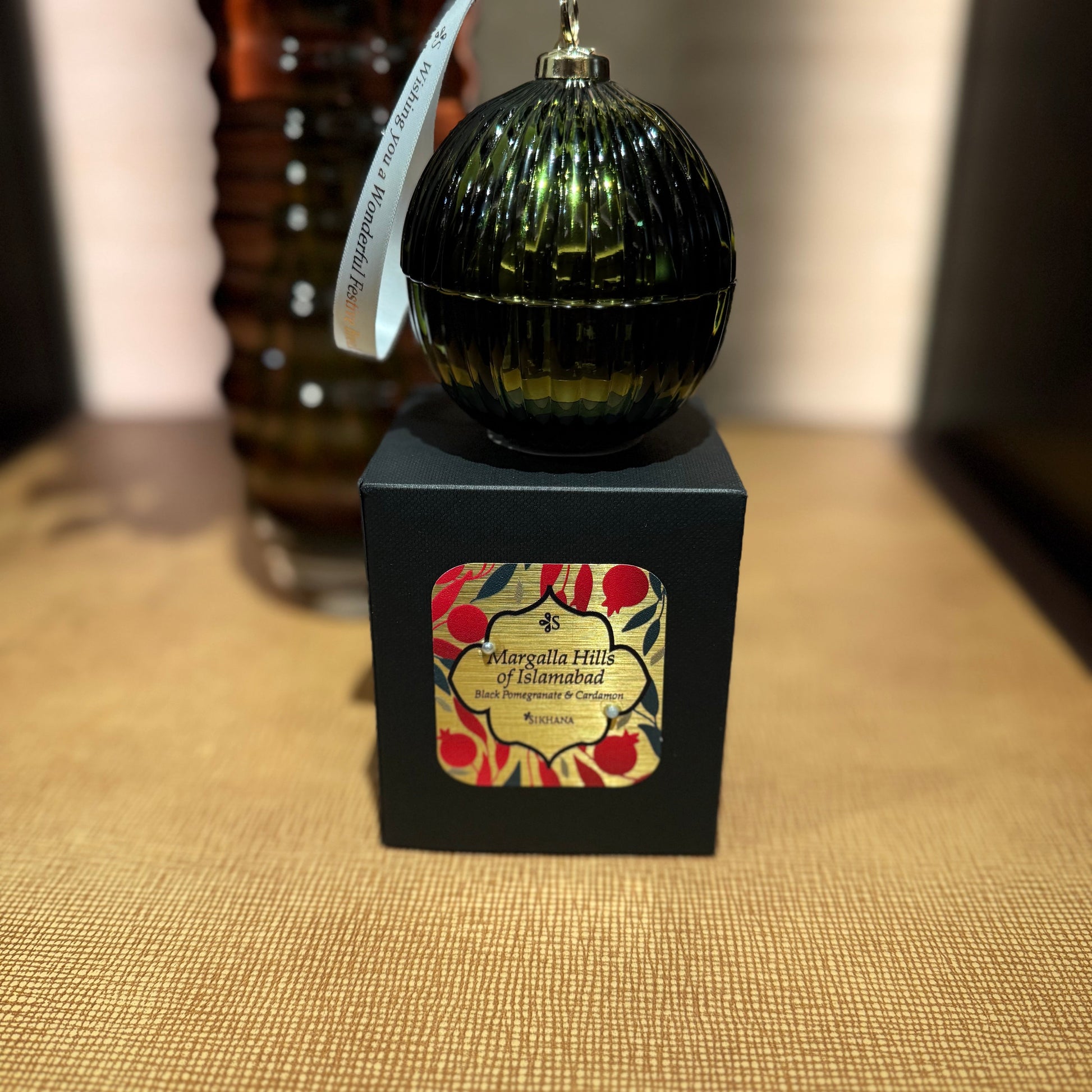 Decorative ornament on a black box with floral design, placed on a textured surface.