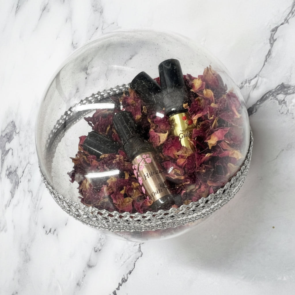 Decorative glass sphere with dried flowers and small bottles on a marble surface