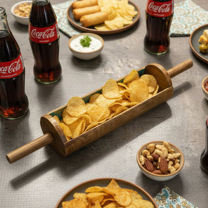 Coca-Cola bottles with a rolling pin filled with chips on a table with snacks and drinks.