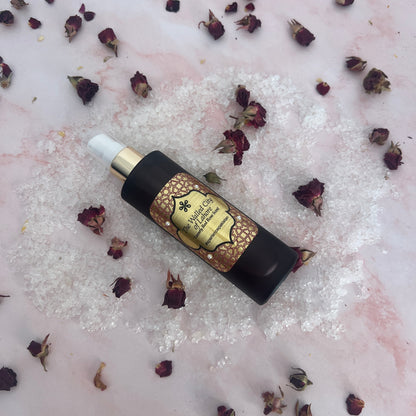 Skincare body oil bottle with decorative label on a textured surface with dried flowers