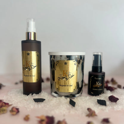 Oud Bundle with bath salts, body oil and handcream with gold labels on a textured surface with dried flowers.