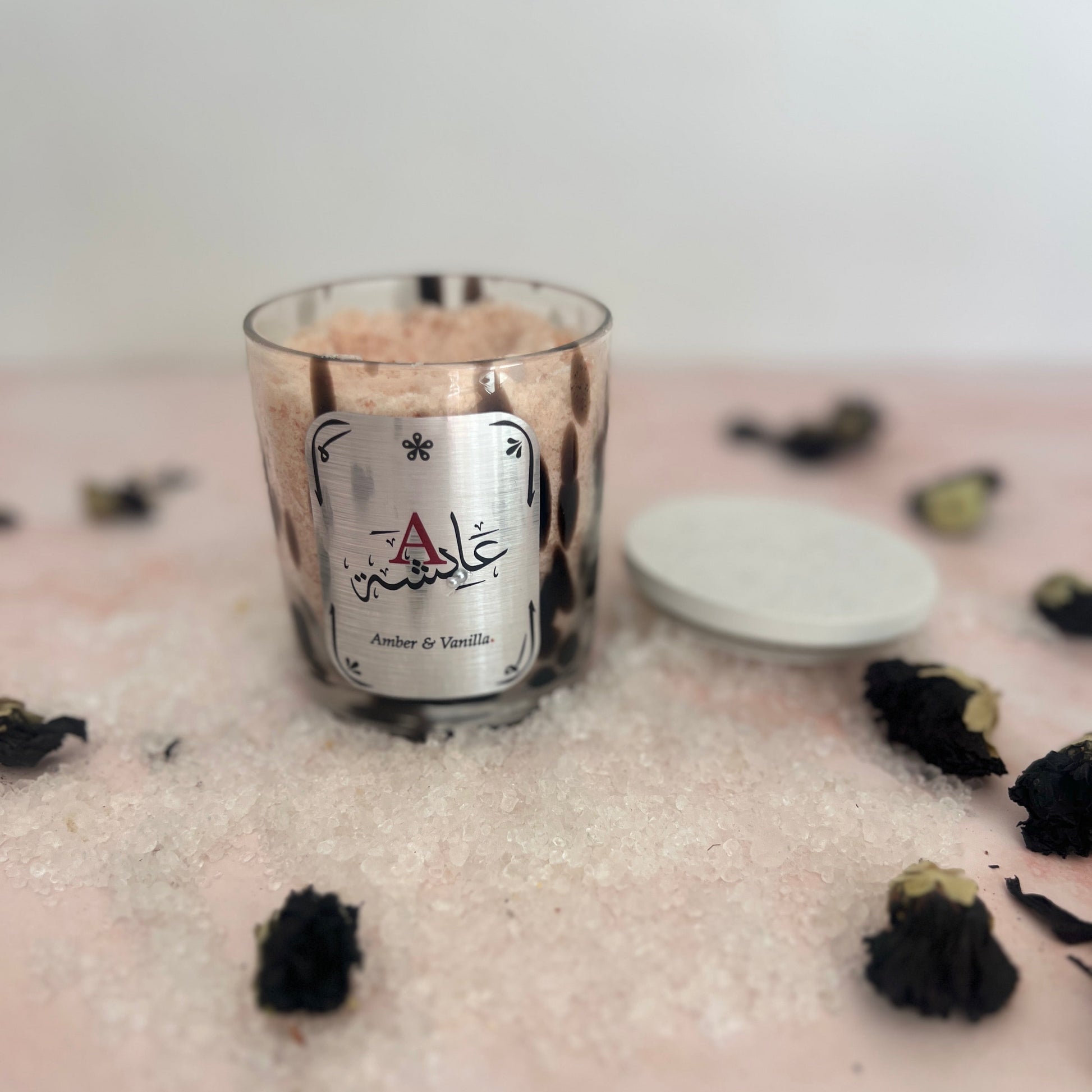 Bath Salts with a brand label on a surface with black dried flowers
