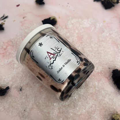 Bath Salts in a glass jar with a label on a textured pink surface with black decorative elements.