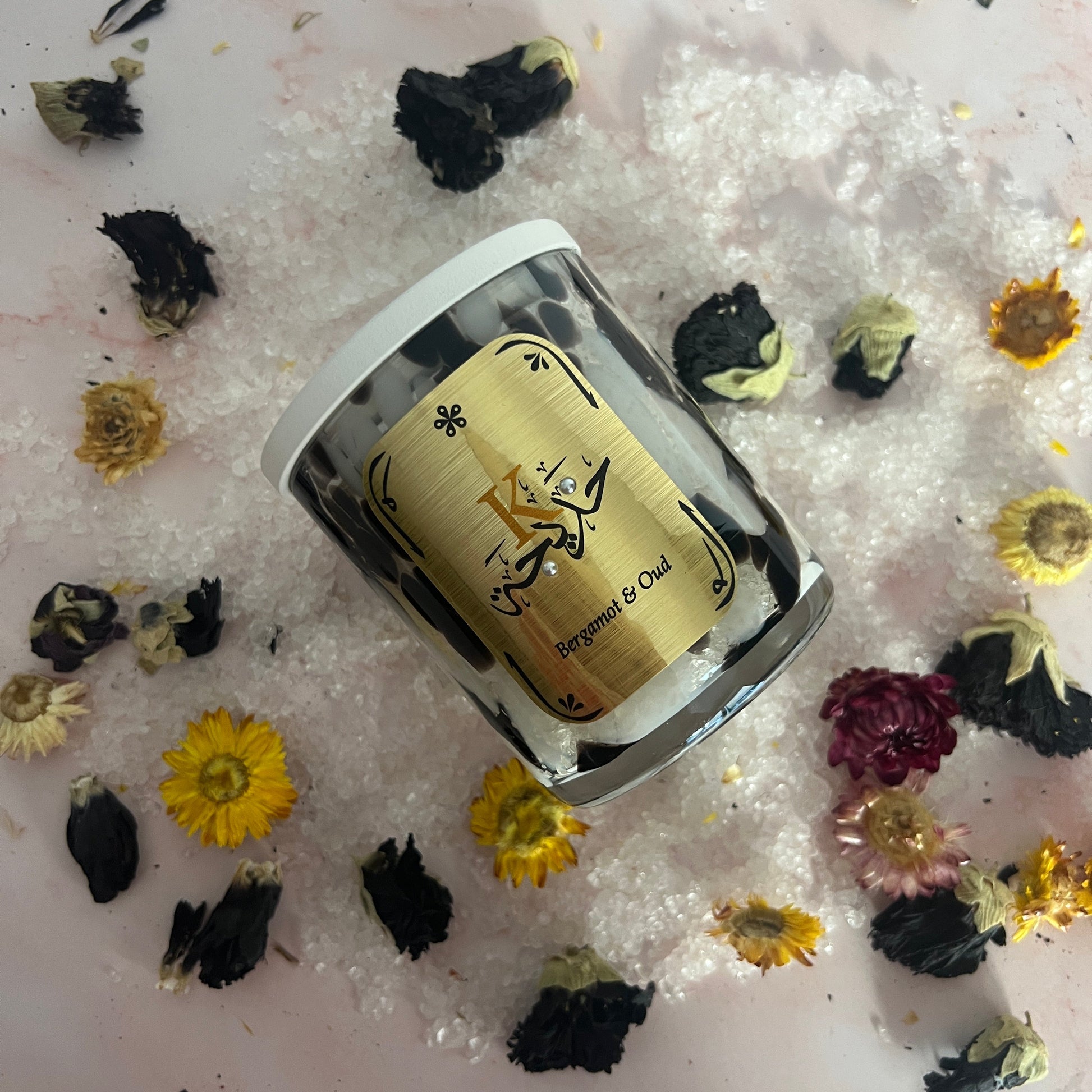 Bath Salts in a clear container with a decorative label on a surface with dried flowers.