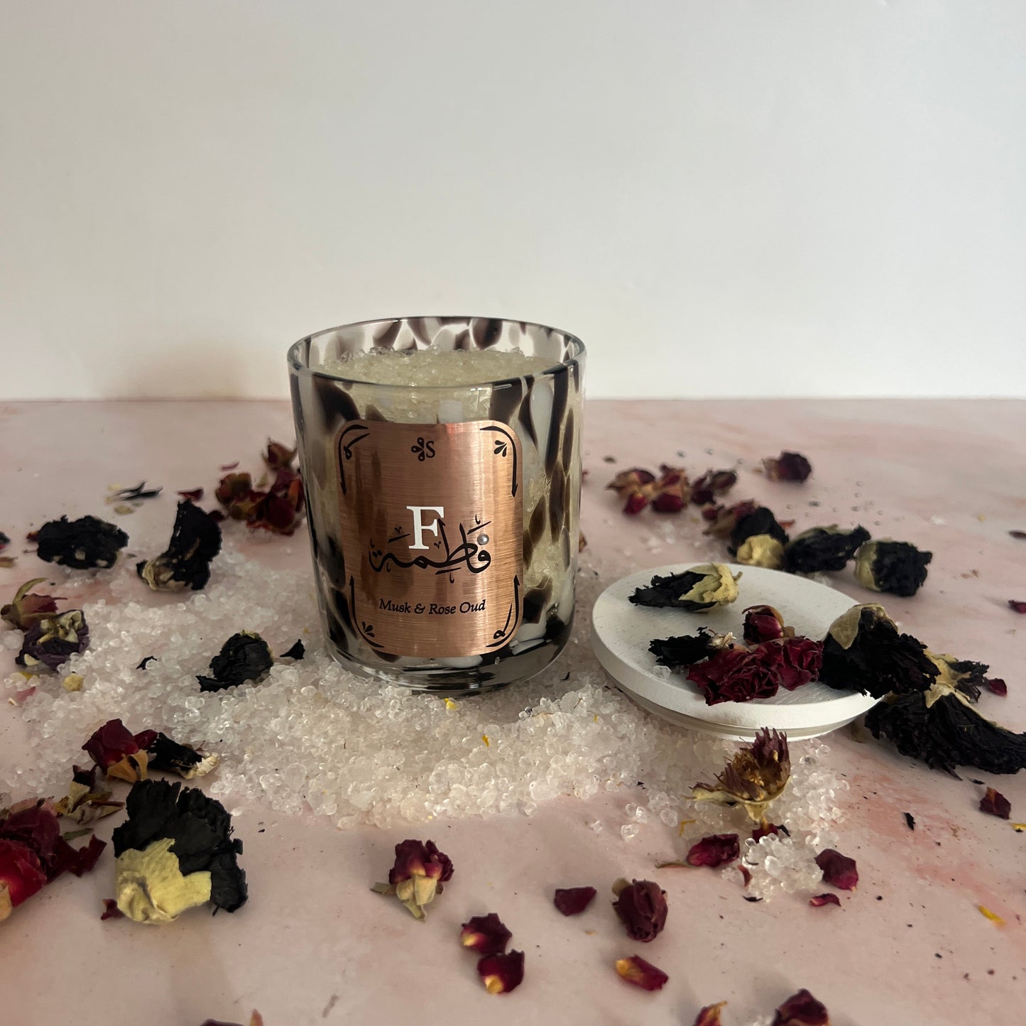 Bath Salts with rose petals scattered around it.