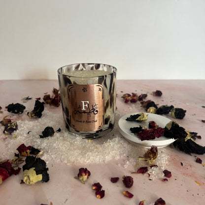 Bath Salts with rose petals scattered around it.