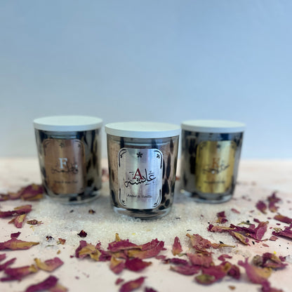 Three small cylindrical containers with lids on a white surface with dried flowers.
