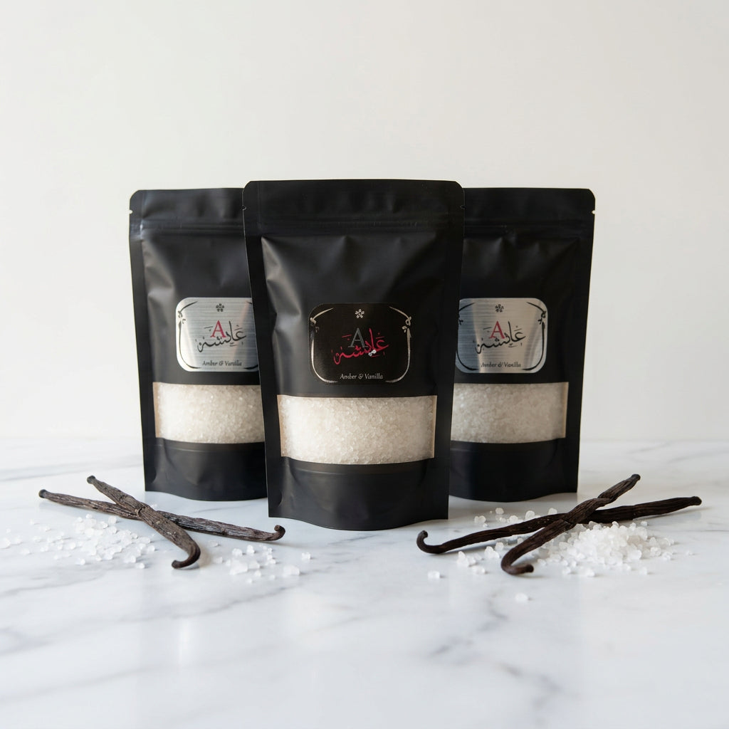 Three black stand-up pouches of a product with silver and red labels, displayed on a glass-topped side table in a bedroom setting.