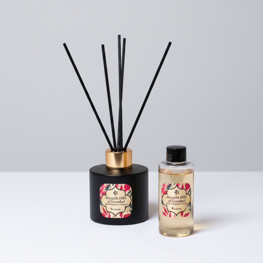 Reed diffuser and bottle with floral label on a neutral background