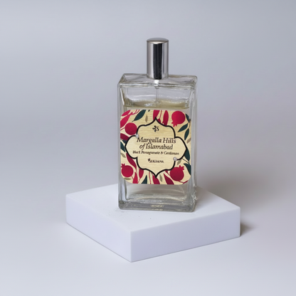 Perfume bottle with a pomegranate and cardamom theme on a neutral background