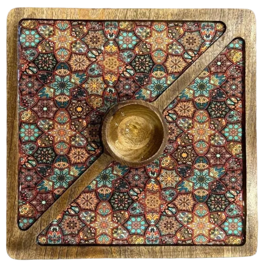 A square wooden game board with a colorful geometric pattern and a central wooden cup, photographed from above on a white background.