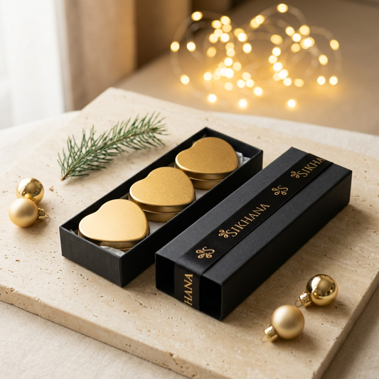 Sikhana three-piece solid perfume gift set styled with evergreen foliage, gold baubles and festive lights